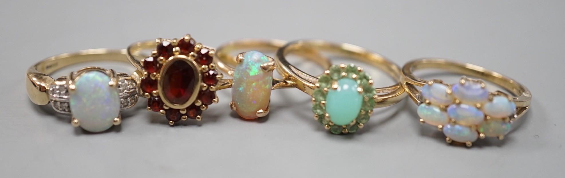 Five assorted modern 9ct gold and gem set dress rings, including white opal and diamond chip cluster, white opal cluster and garnet cluster